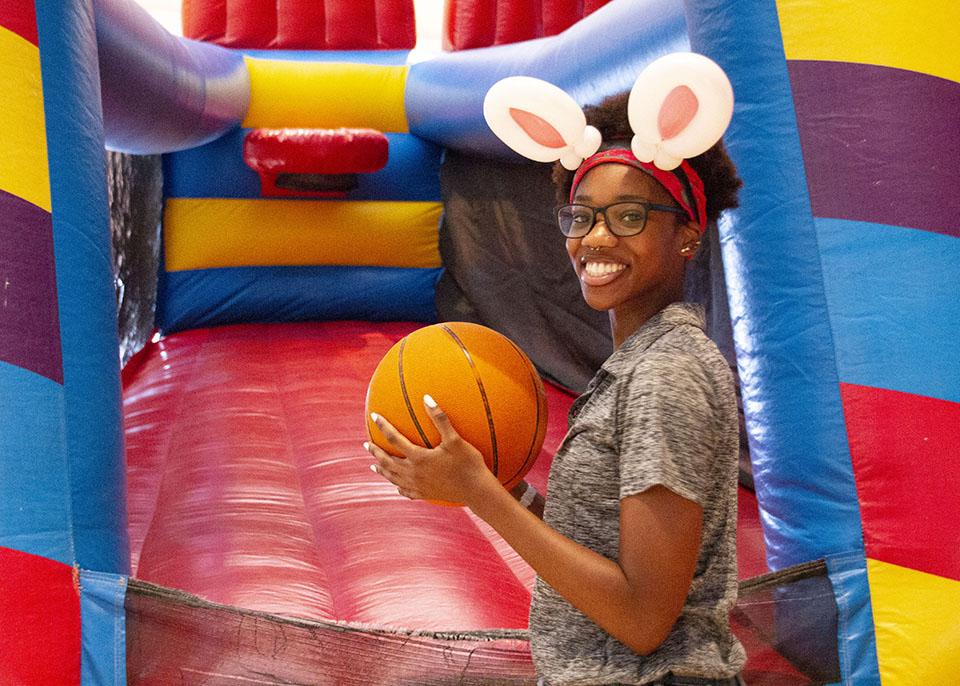 female student wearing bunny ears headband and holding a basketball