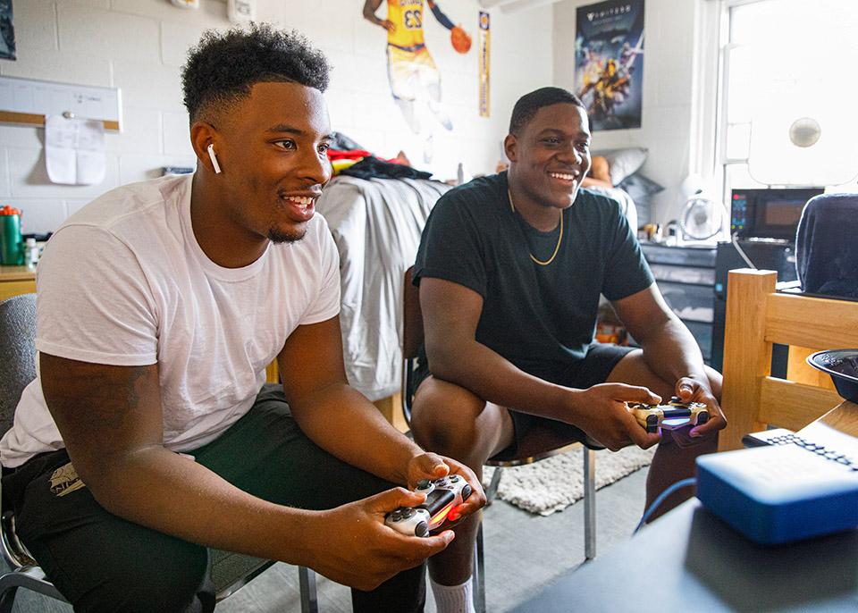 males students playing video game in dorm room