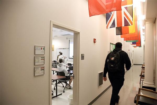 A student walks underneath a group of international flags when exiting a classroom